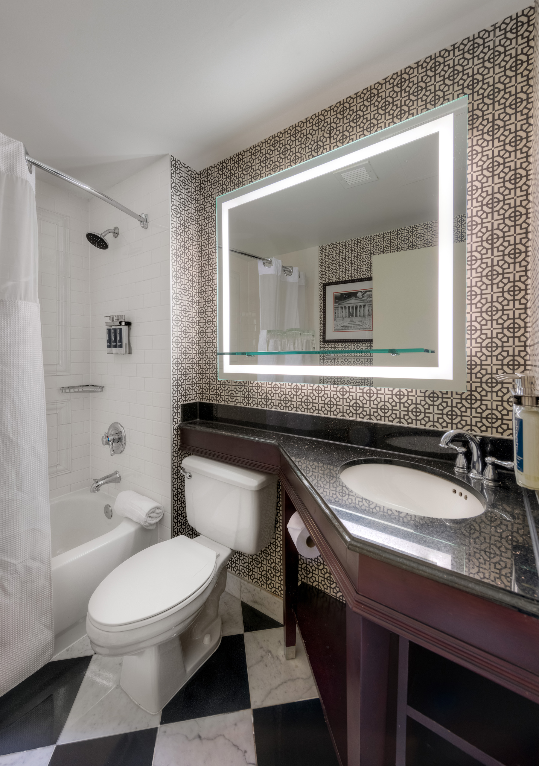 Modern guest bathroom at Hamilton Hotel DC with illuminated vanity mirror and marble finishes