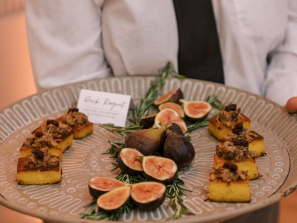Server holding tray of fig and crostini appetizers