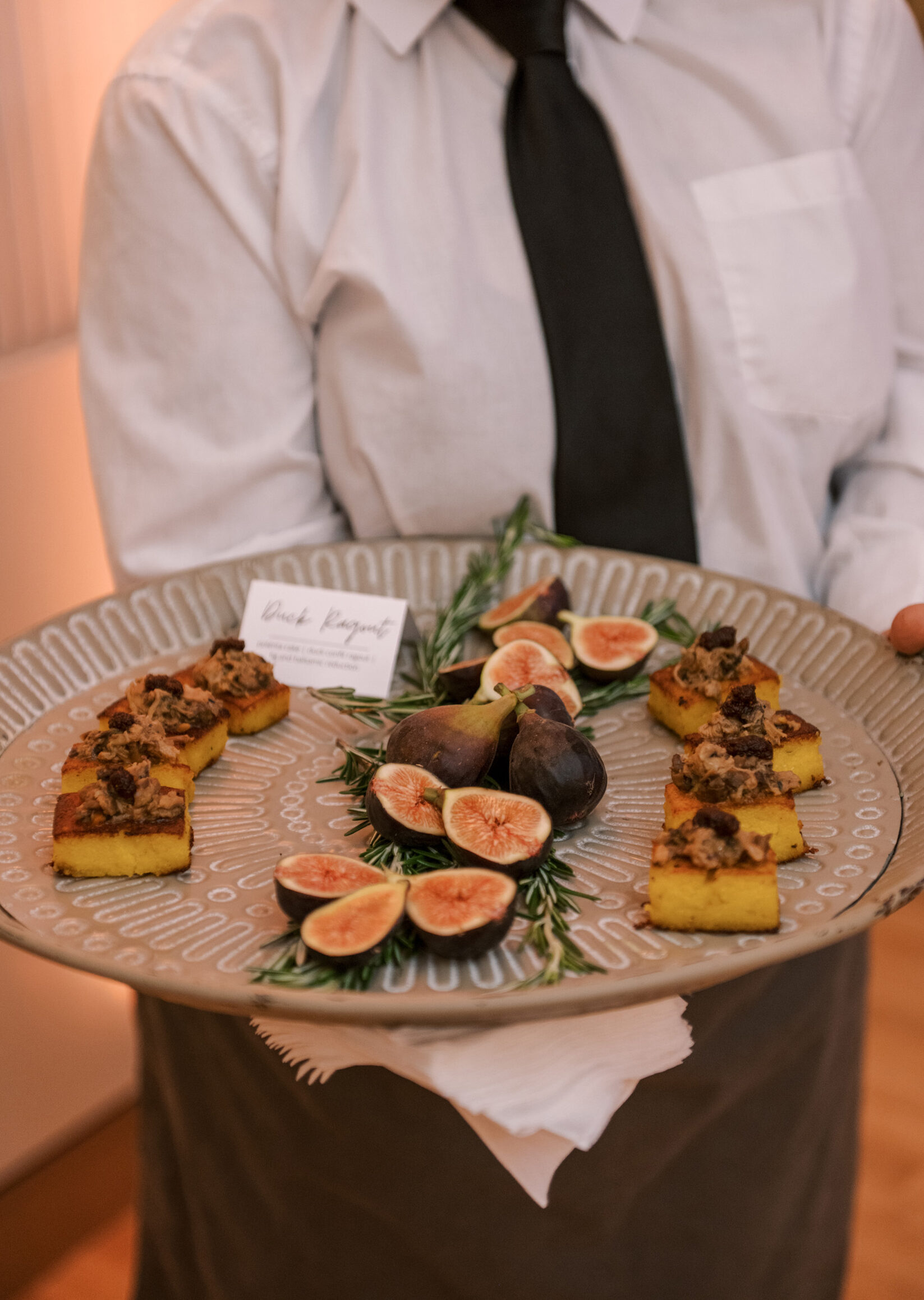 Server holding tray of fig and crostini appetizers
