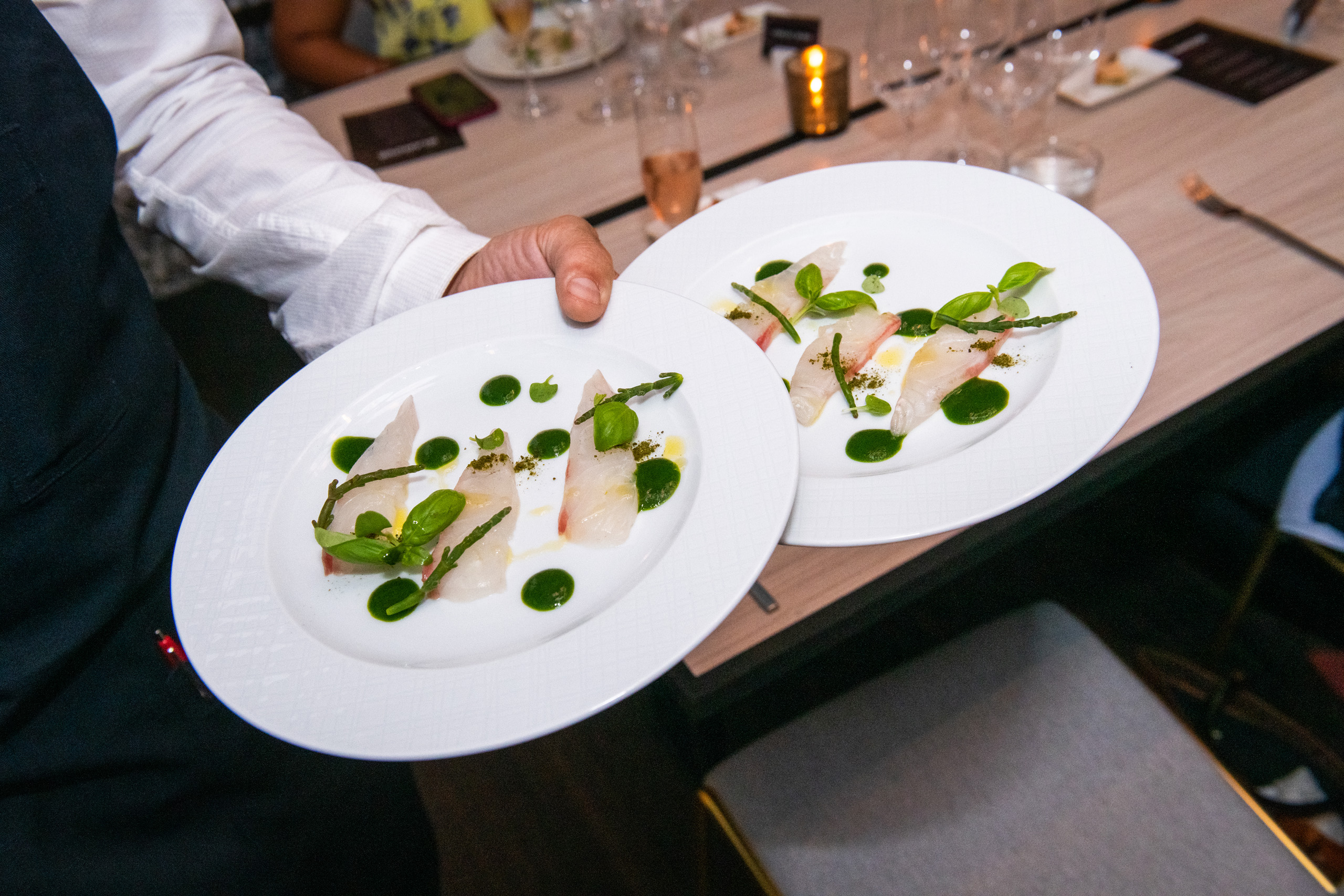 Chef presenting artfully plated seafood dishes.