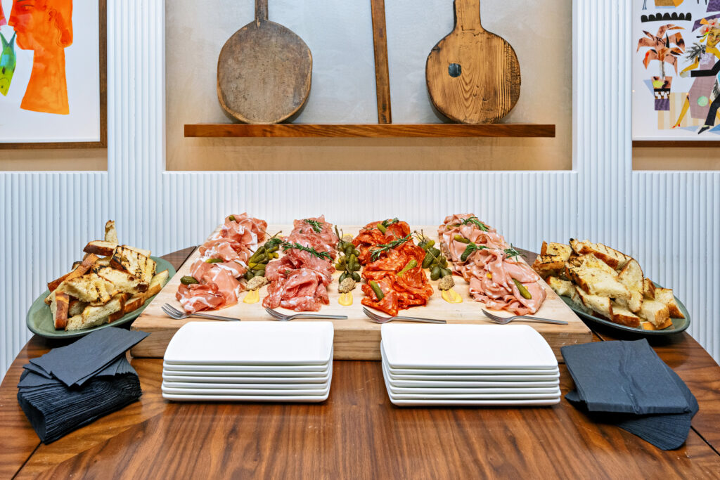 Charcuterie board with cured meats, bread, and plates.