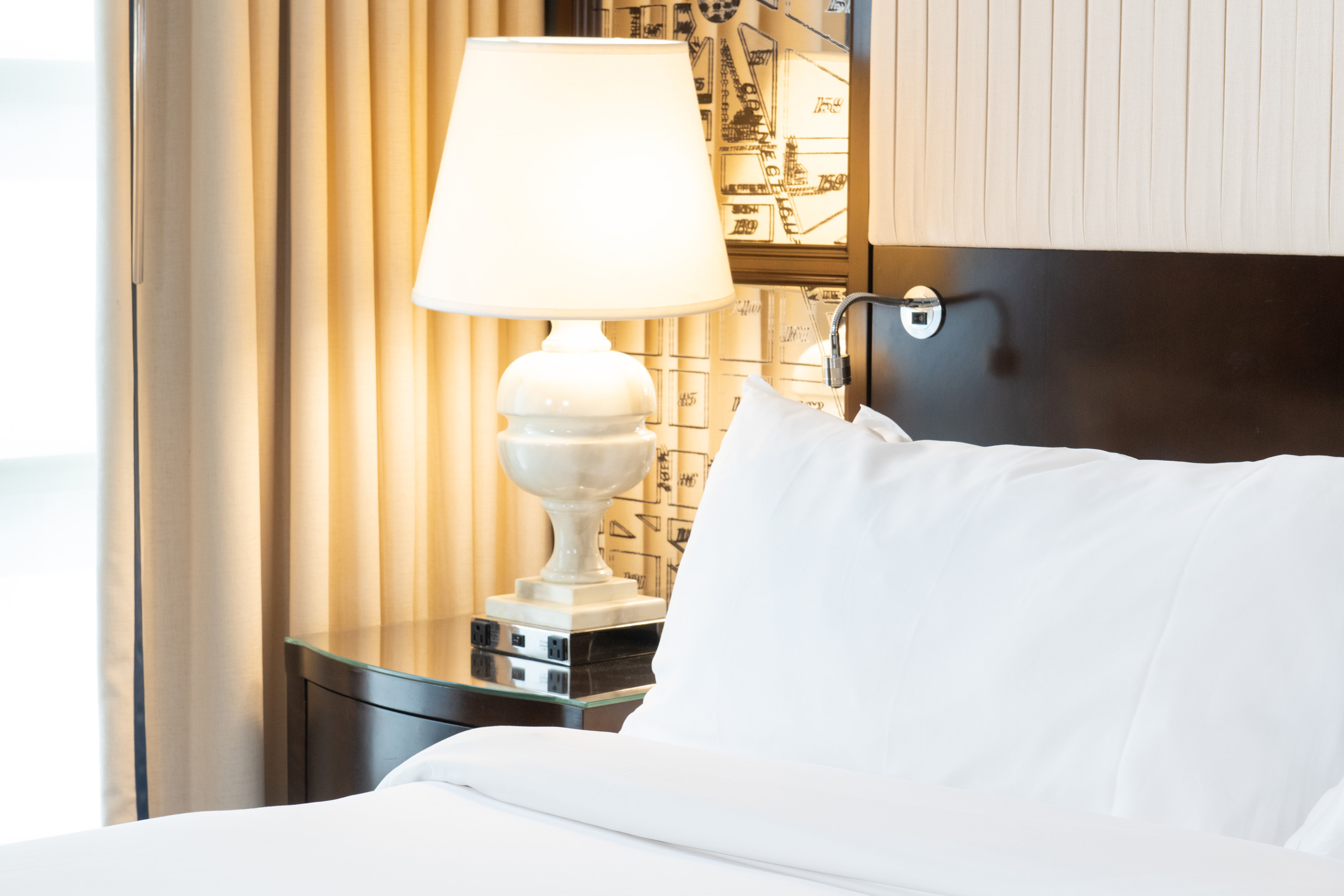 Bedside lamp and plush white bedding.