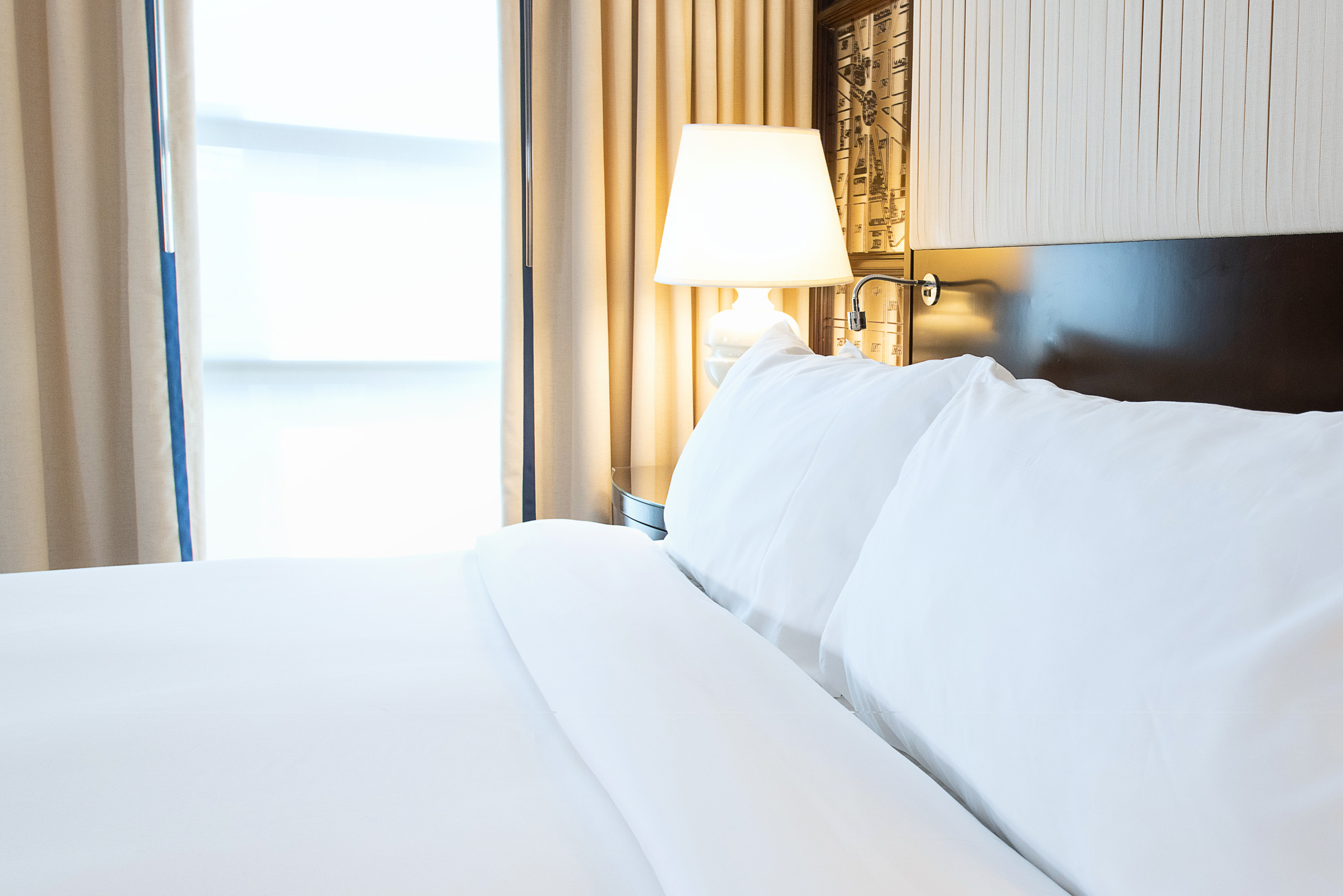 Plush white bedding beside glowing lamp.