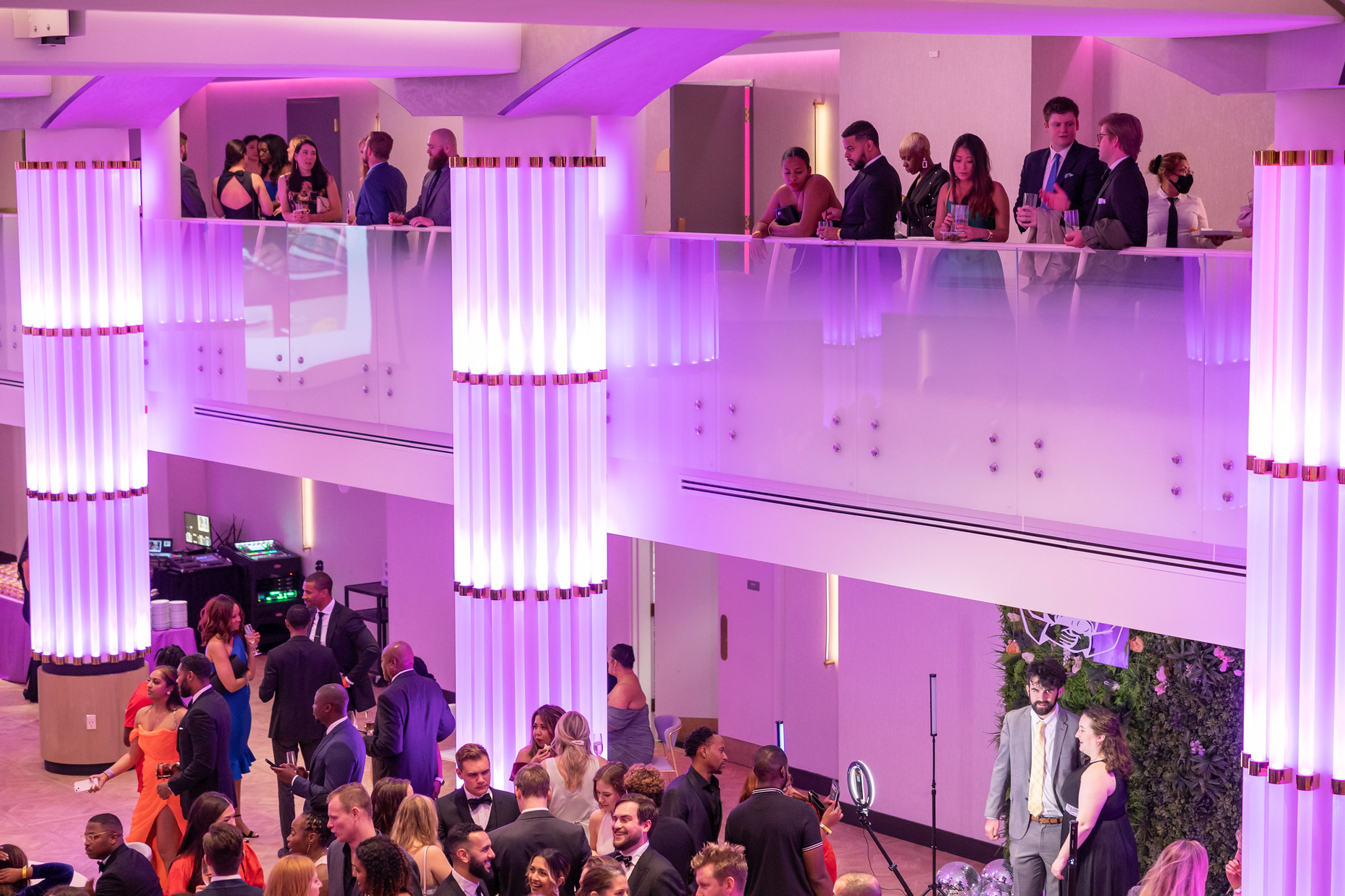 Cocktail reception on balcony with purple lighting.