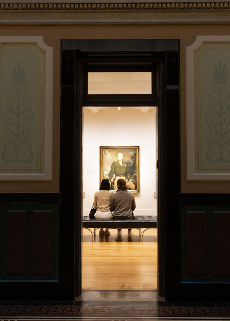 Museum visitors viewing portrait in gallery.