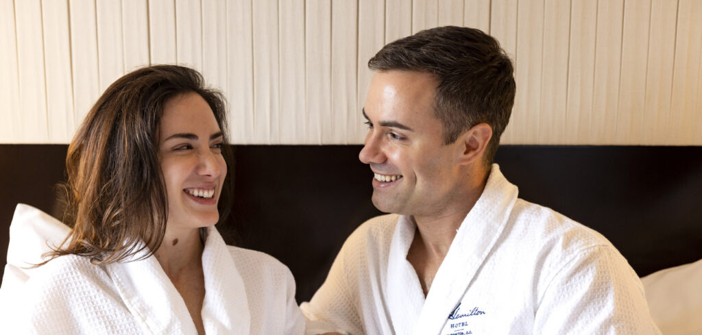 Couple enjoying coffee in plush hotel robes.