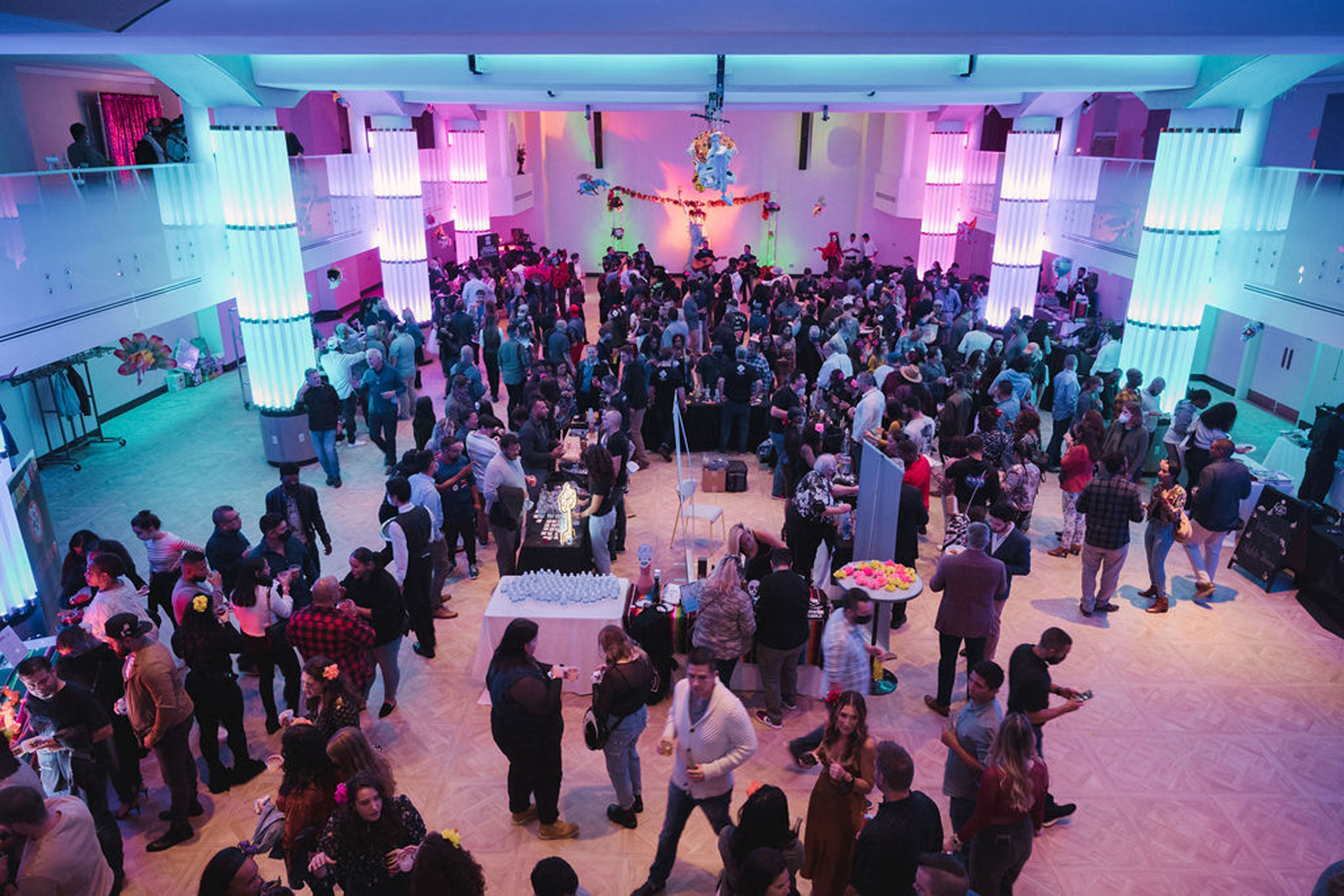 Large crowd mingling in colorful lit atrium