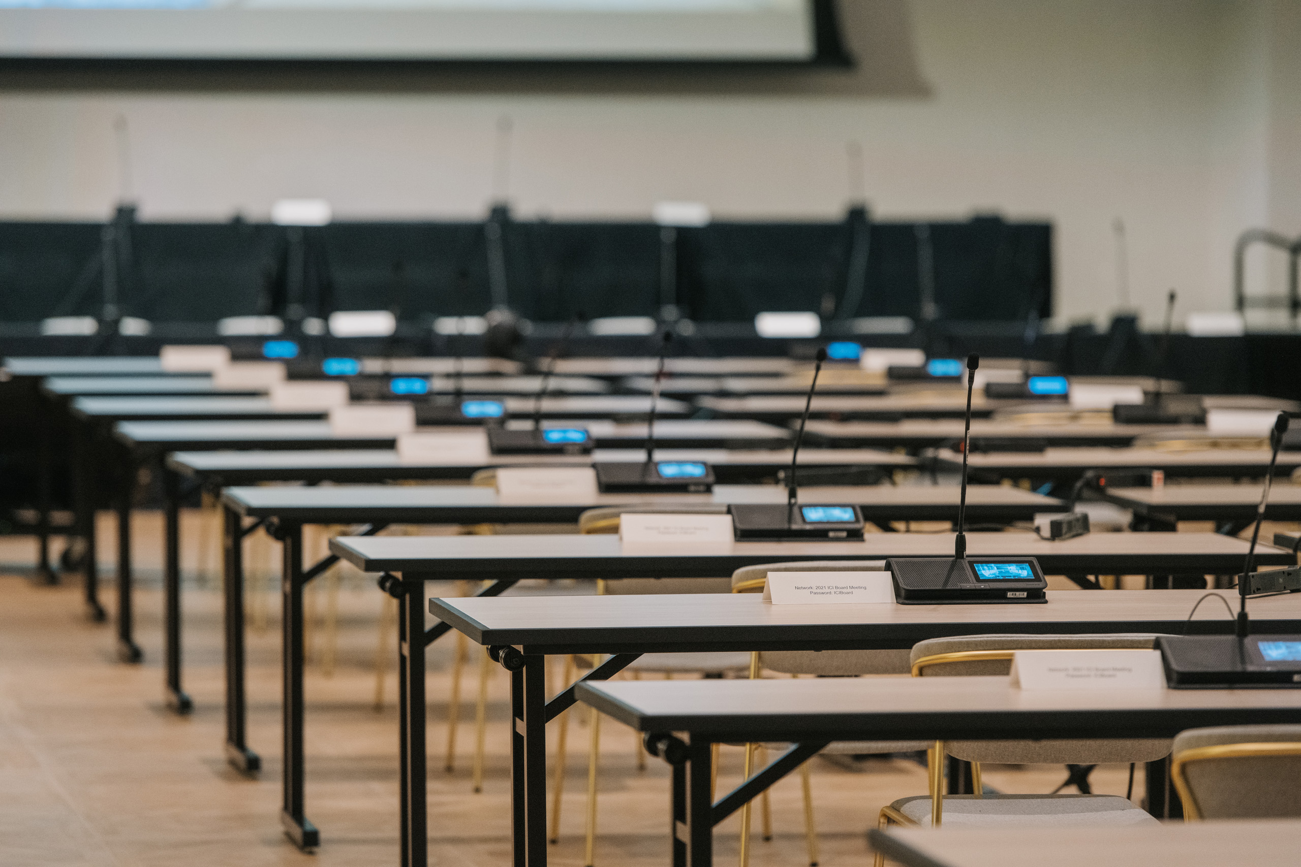 Classroom-style meeting setup with microphones and nameplates