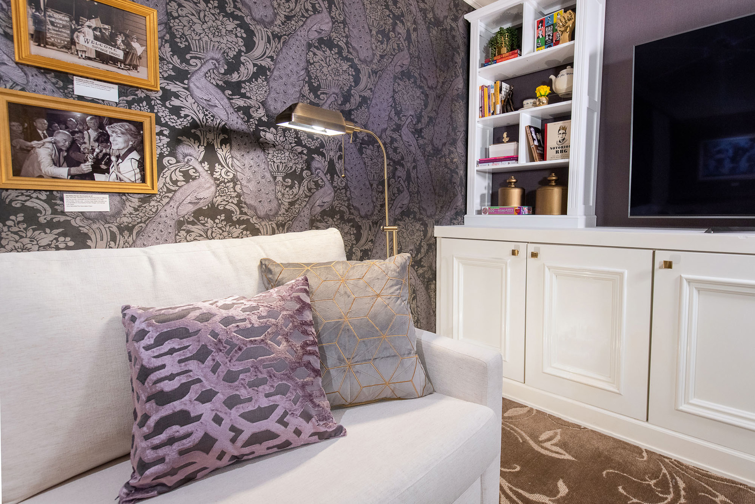 Cozy corner sofa beside ornate wallpaper.