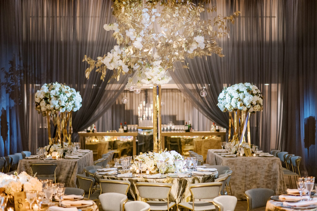 Elegant reception tables with tall floral centerpieces.