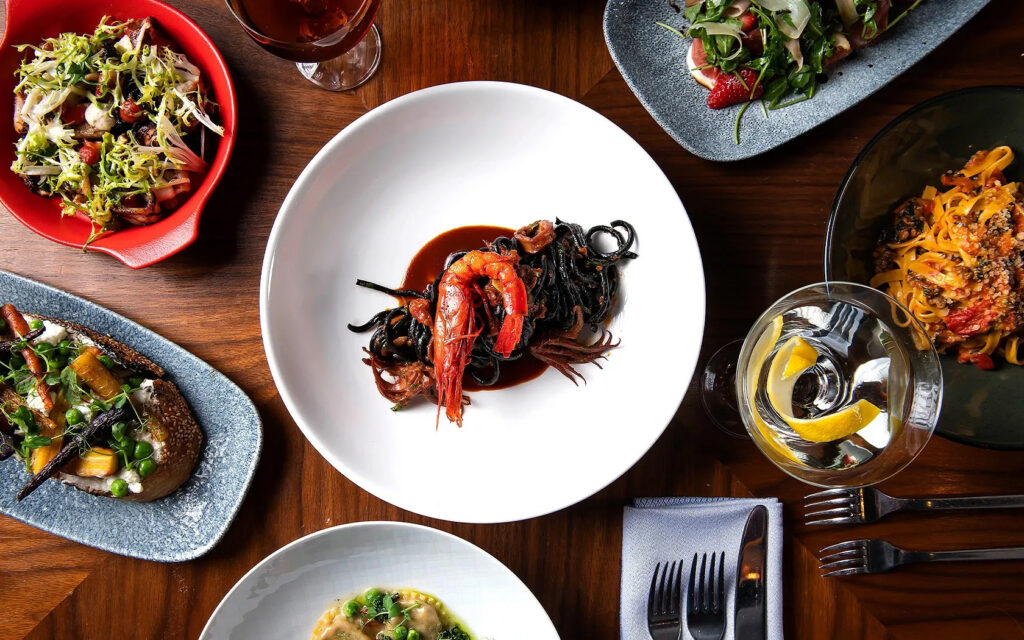 Overhead view of seafood pasta and colorful dishes.