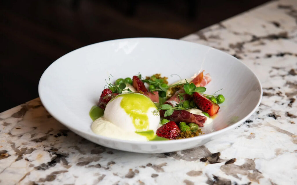 Burrata with strawberries, peas, and prosciutto.