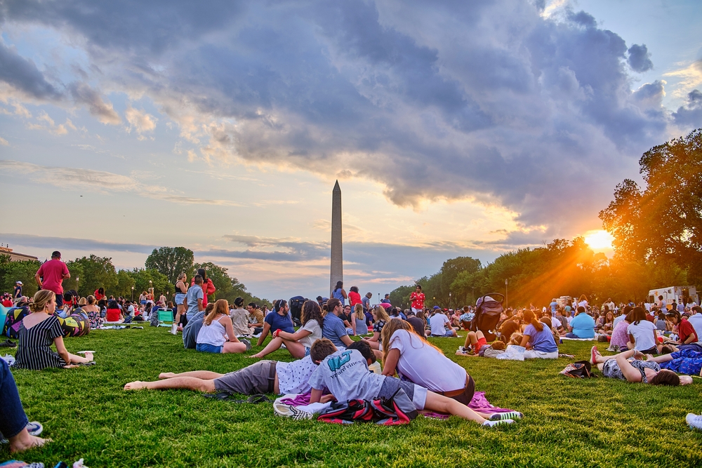 families sitting on grass in front of washington dc monument