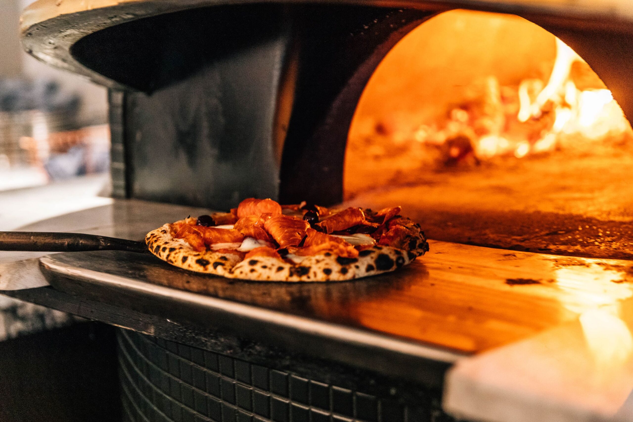 Pizza slides into pizza oven.